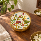 Bird Motif Soy Wax Candle in a Brass Urli, 4 in, on a teak console in daylight